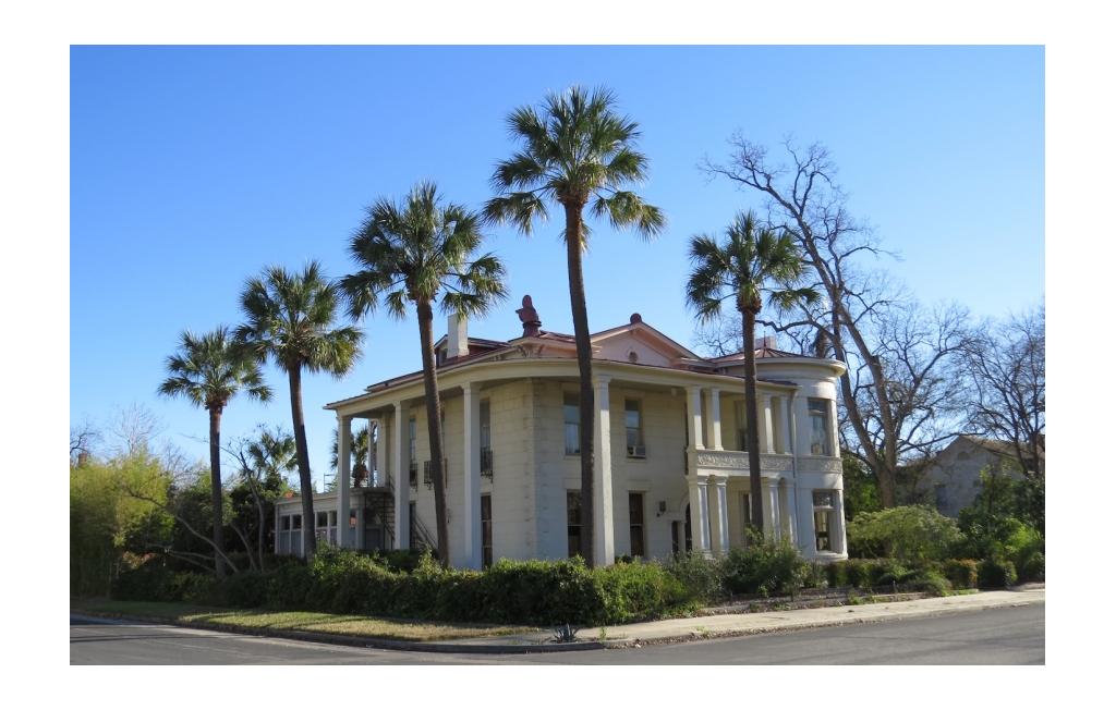 Large home with palm trees lining the landscaping.
